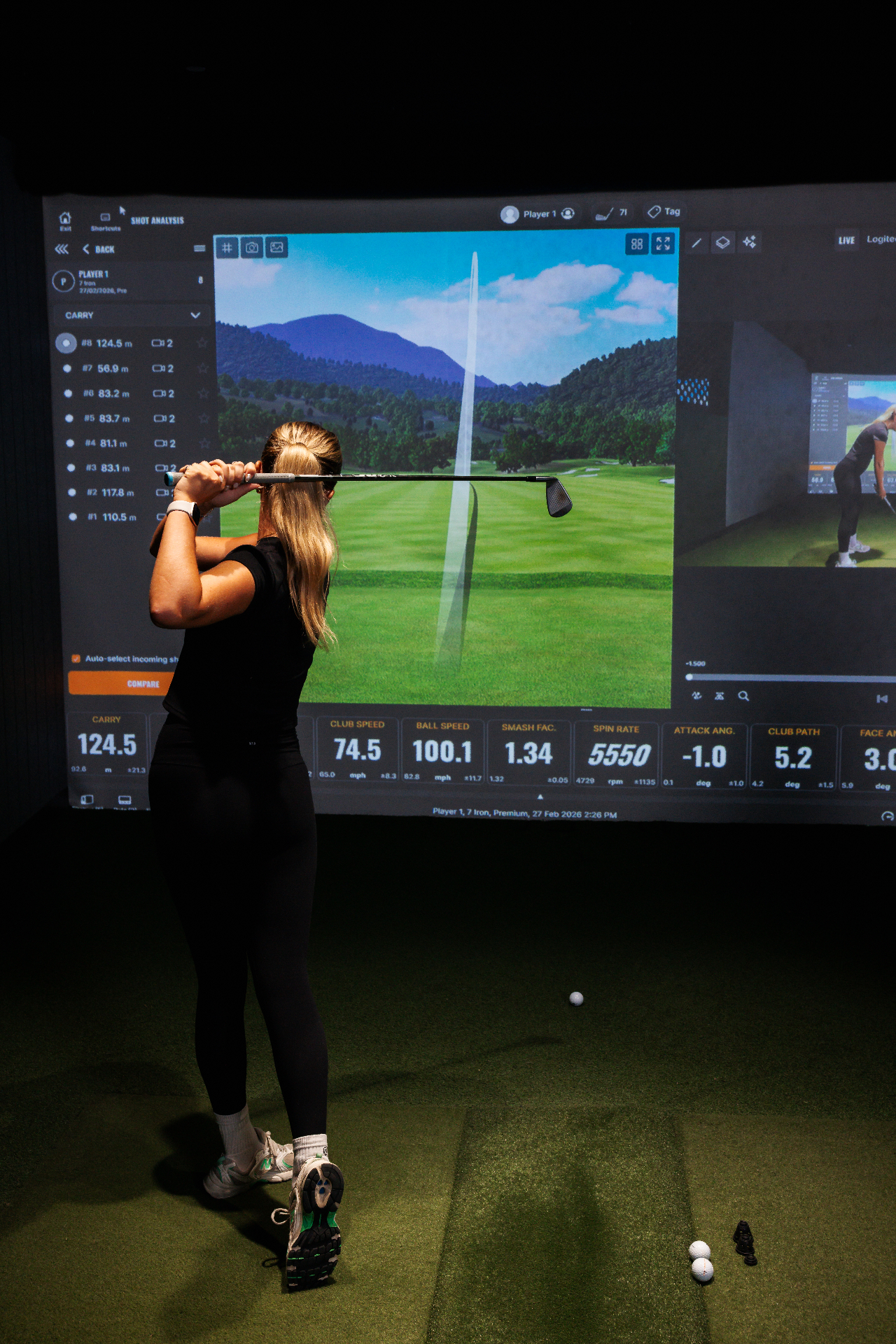 Golfer with iron play on the course simulator, carry and total data visible.